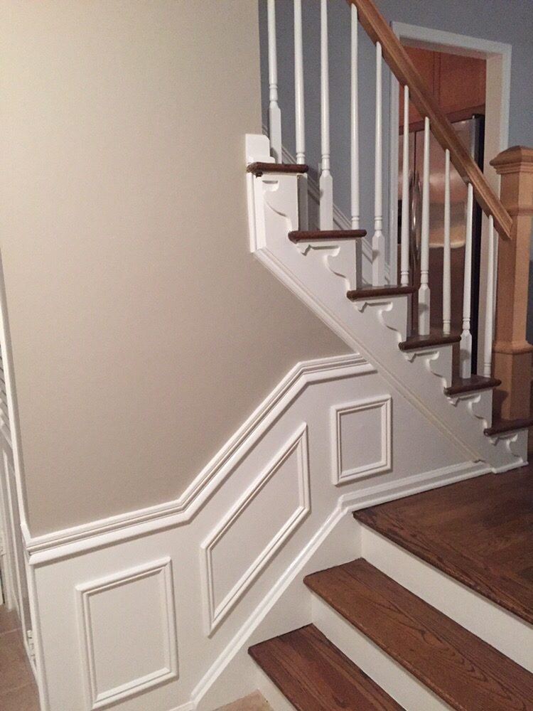 Repainted staircase with crisp white wainscoting, panel moulding, and neutral walls