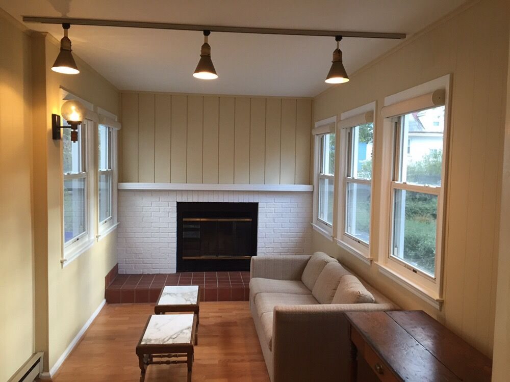 Sunroom transformed: red brick fireplace painted clean white, wood paneling refreshed in warm cream