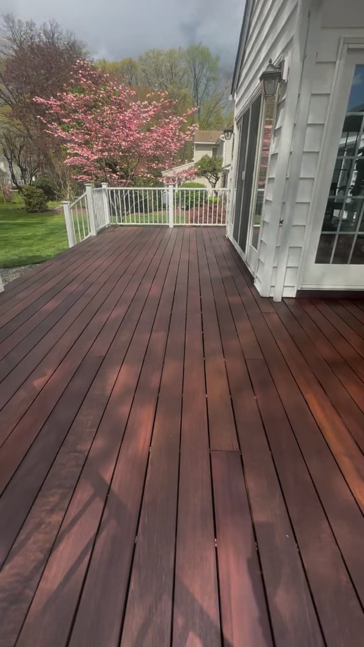 Wood deck stained a rich mahogany, framed by crisp white railings and a blooming spring dogwood